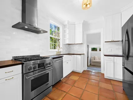 a kitchen with stainless steel appliances granite countertop a stove a refrigerator and a white cabinets