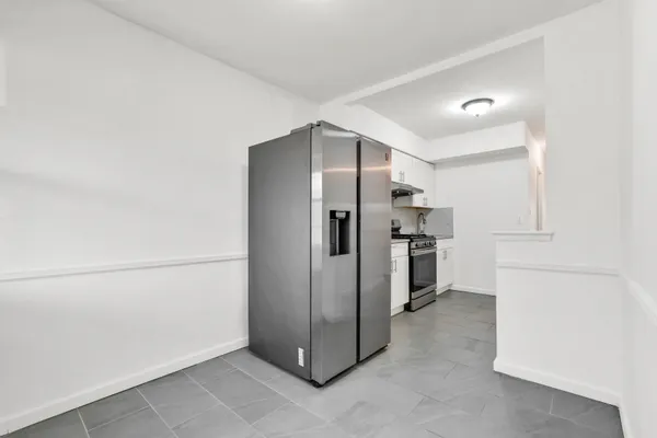 a view of a kitchen with refrigerator and white cabinets