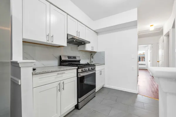 a kitchen with stainless steel appliances granite countertop white cabinets and a stove