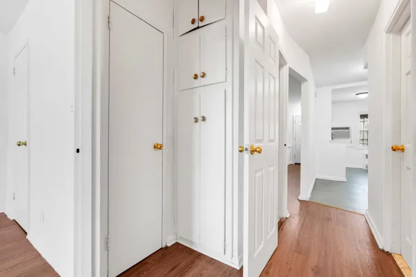 a view of a hallway with wooden floor and closet area