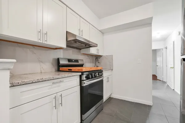 a kitchen with stainless steel appliances granite countertop white cabinets and a stove