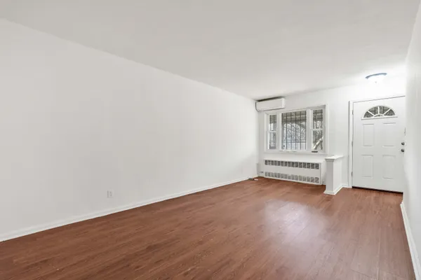 an empty room with wooden floor and window