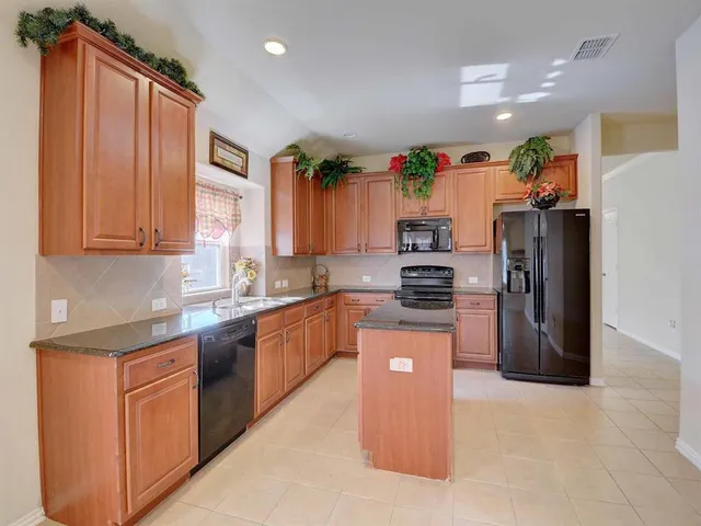 a kitchen with stainless steel appliances granite countertop a refrigerator sink and stove