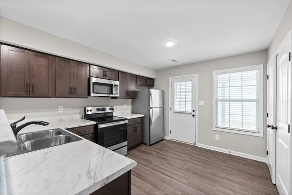 a kitchen with stainless steel appliances granite countertop a sink a stove a refrigerator cabinets and wooden floor