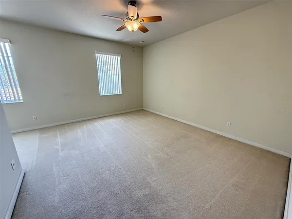 an empty room with a chandelier fan and windows