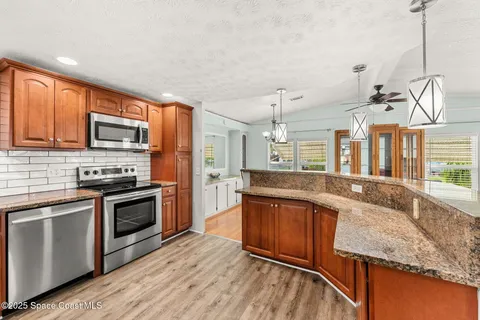 a large kitchen with granite countertop stainless steel appliances and wooden cabinets