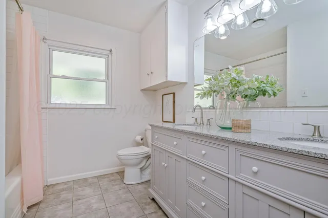 a bathroom with a granite countertop sink a toilet and a mirror