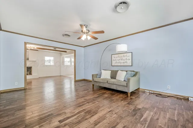 a living room with couches and a view of kitchen with wooden floor