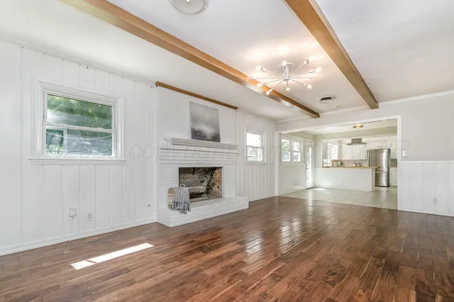 a view of an empty room with wooden floor fireplace and a window
