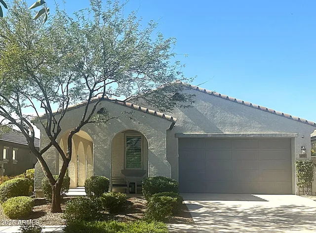 a front view of a house with garden and trees