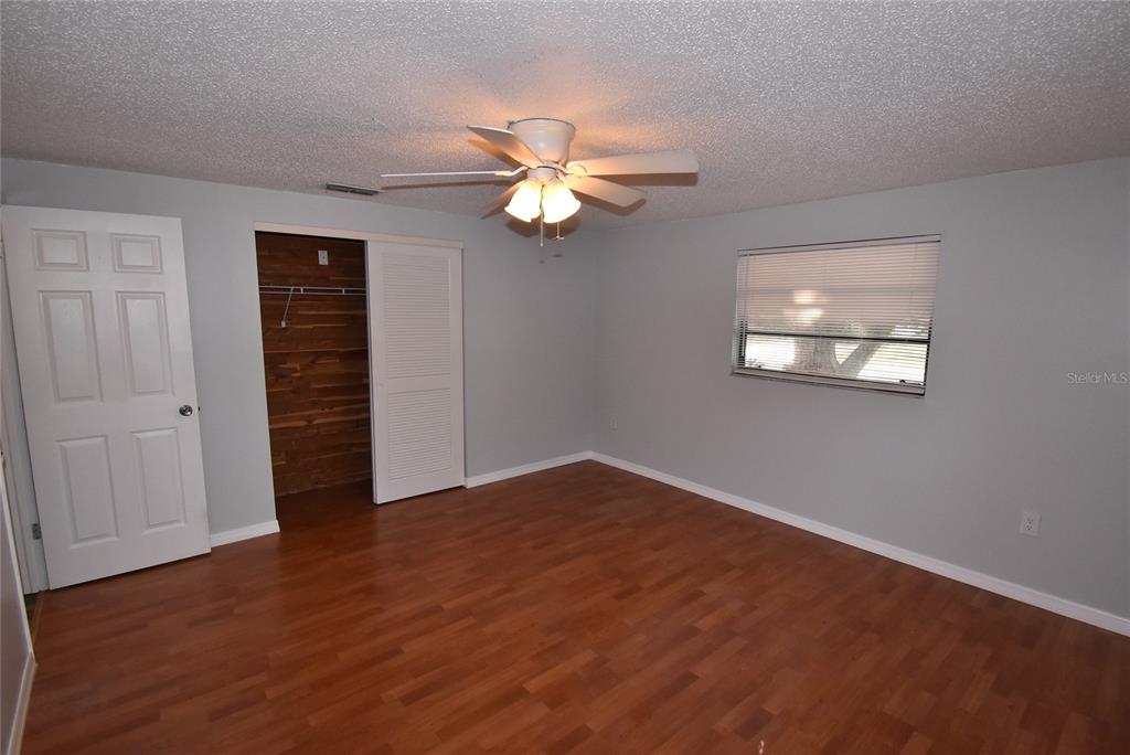 7615 Karen Drive Port Richey, FL 34668 - Photo 15 of 24 an empty room with wooden floor chandelier fan and windows