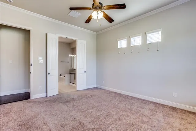 an empty room with chandelier fan and windows