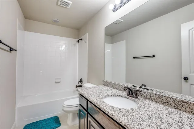 a bathroom with a granite countertop sink toilet mirror and shower