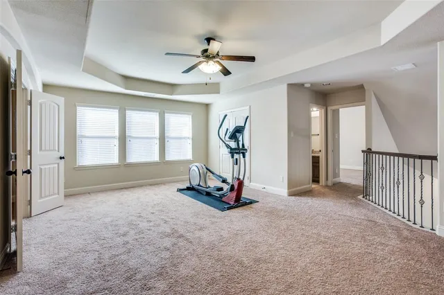 an empty room with ceiling fan and windows