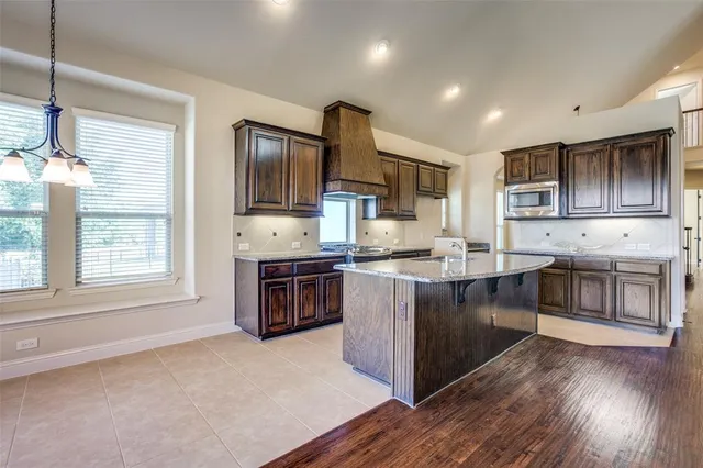 a kitchen with stainless steel appliances kitchen island granite countertop a stove a sink and a refrigerator