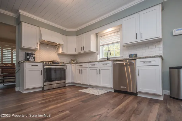 a kitchen with granite countertop wooden floors and white stainless steel appliances