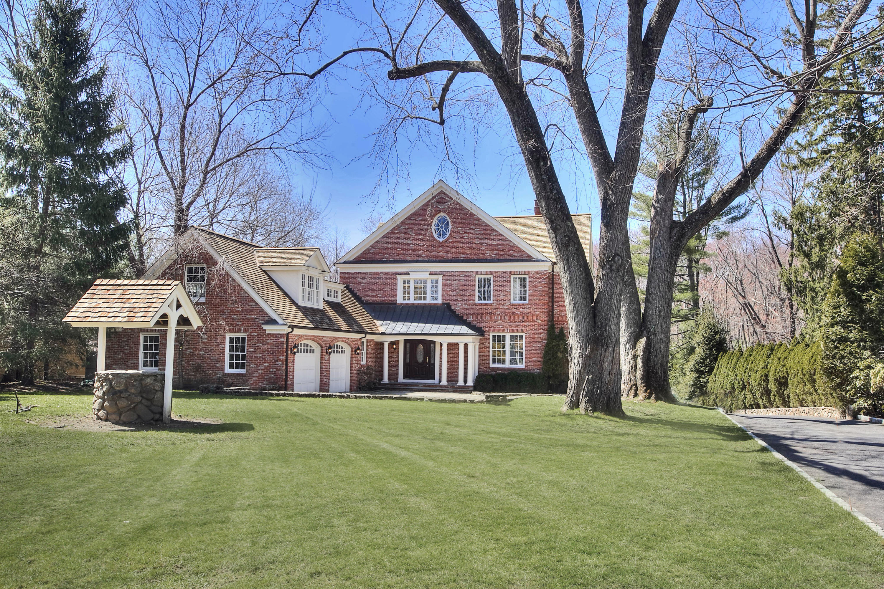 320 Ponus Ridge Road New Canaan, CT 06840 - Photo 2 of 40 a front view of a house with a garden and trees