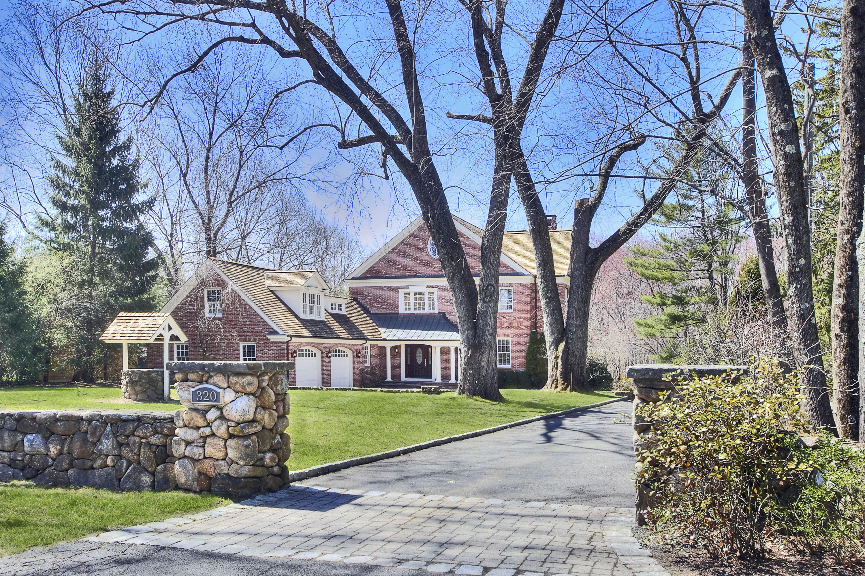 320 Ponus Ridge Road New Canaan, CT 06840 - Photo 3 of 40 a front view of a house with a garden and trees