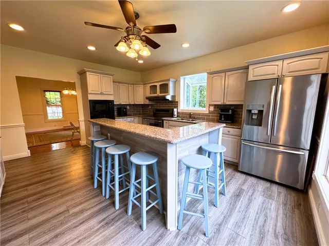 a kitchen with stainless steel appliances a refrigerator a stove a sink dishwasher and a dining table with wooden floor