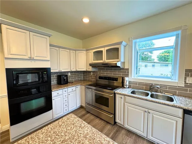 a kitchen with granite countertop a stove sink and microwave