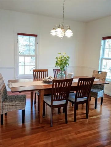 a dining room with furniture wooden floor a chandelier and a rug