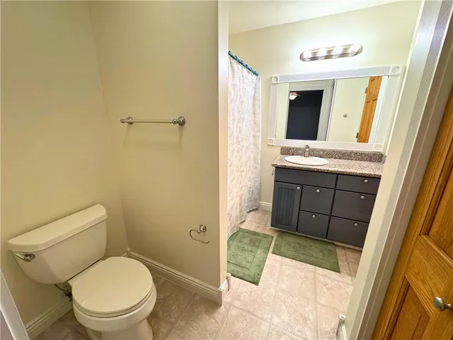 a bathroom with a granite countertop toilet sink and mirror