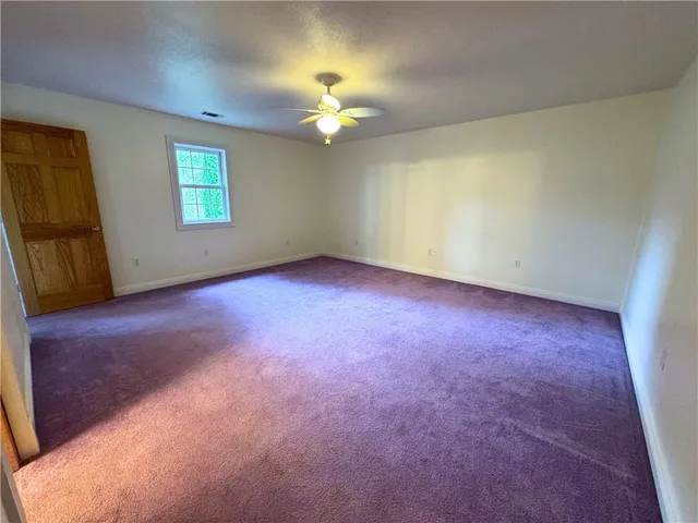 an empty room with a chandelier fan and windows
