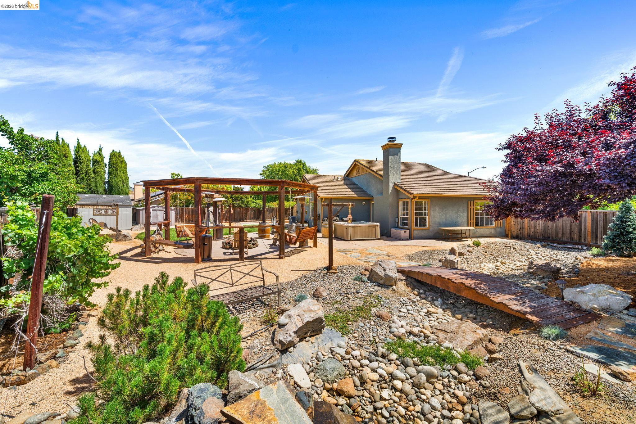 1186 El Rio Court Livermore, CA 94551 - Photo 35 of 60 Expansive backyard featuring a custom wooden pergola, a dry river bed with a wooden bridge, and a terraced landscape
