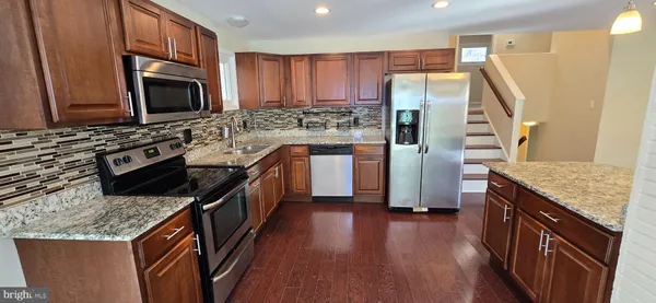 a kitchen with stainless steel appliances granite countertop a refrigerator a stove top oven a sink and dishwasher