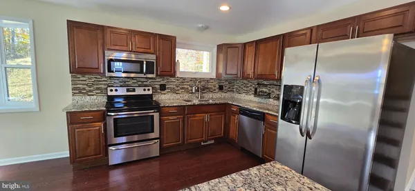 a kitchen with stainless steel appliances wooden cabinets a stove a refrigerator and a microwave