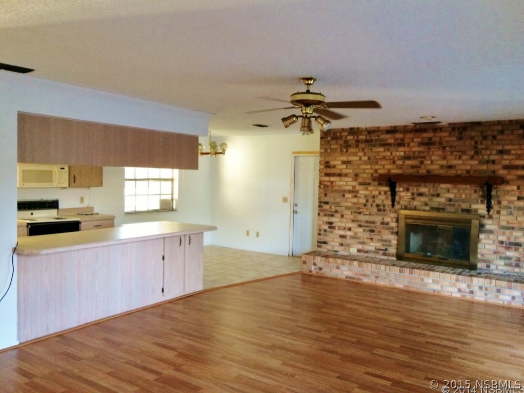 509 Cardinal Drive Edgewater, FL 32141 - Photo 4 of 10 a large kitchen with a wooden floor and a fireplace