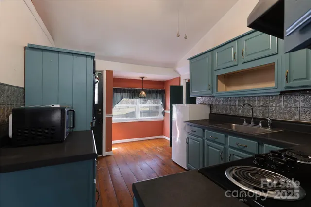 a kitchen with stainless steel appliances a stove a sink dishwasher and microwave with wooden floor