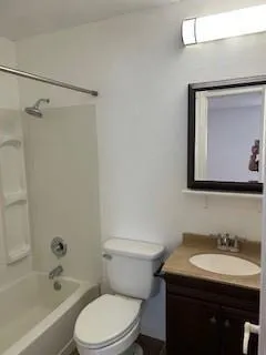 a bathroom with a toilet sink vanity tub and mirror
