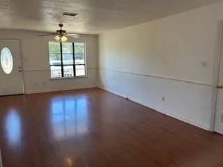 an empty room with wooden floor chandelier and windows