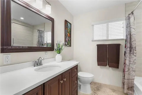 a bathroom with a toilet a sink a vanity a window and mirror