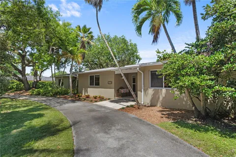 a view of a house with a yard and palm trees