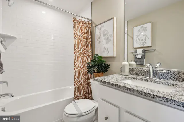 a bathroom with a granite countertop bathtub sink vanity mirror and toilet