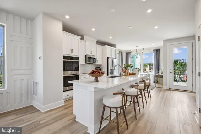 a kitchen with stainless steel appliances a dining table chairs and wooden floor