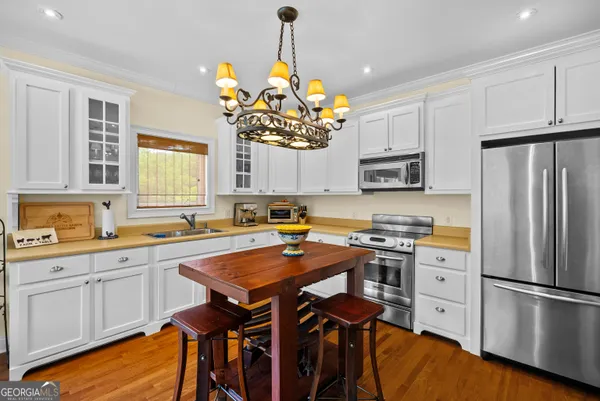 a kitchen with stainless steel appliances a stove a sink dishwasher a refrigerator and a dining table with wooden floor