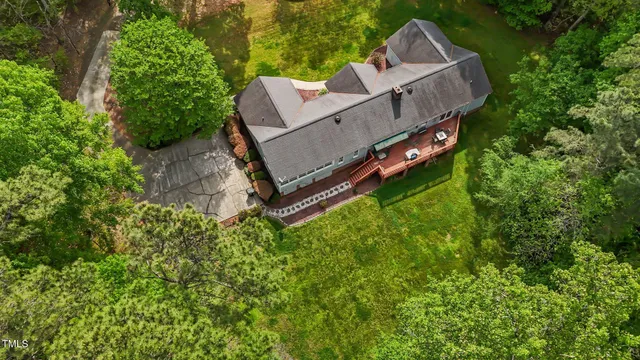 an aerial view of residential house with outdoor space and trees all around