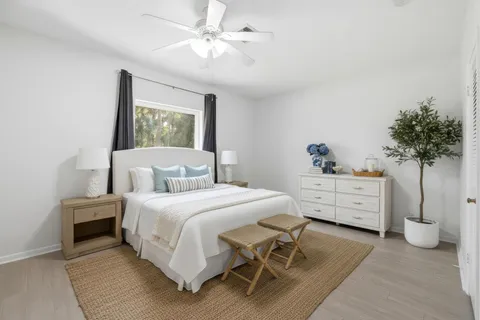 an empty room with wooden floor ceiling fan and windows