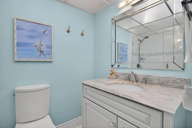 a bathroom with a granite countertop sink a toilet and a mirror