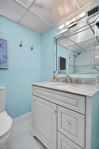 a bathroom with a granite countertop sink a toilet and mirror