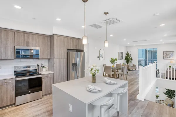 a kitchen with stainless steel appliances kitchen island granite countertop a dining table chairs stove refrigerator and microwave