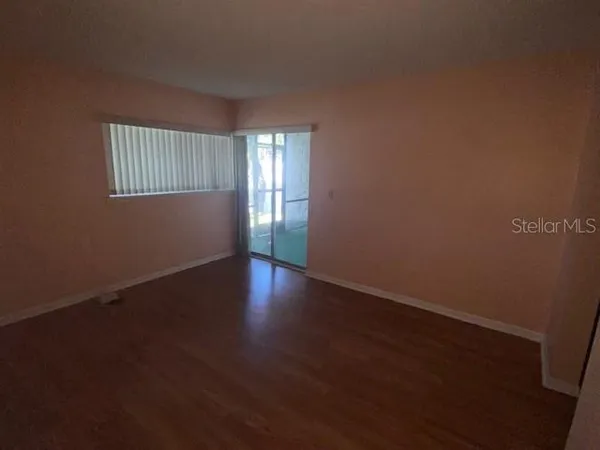 a view of an empty room with wooden floor and a window