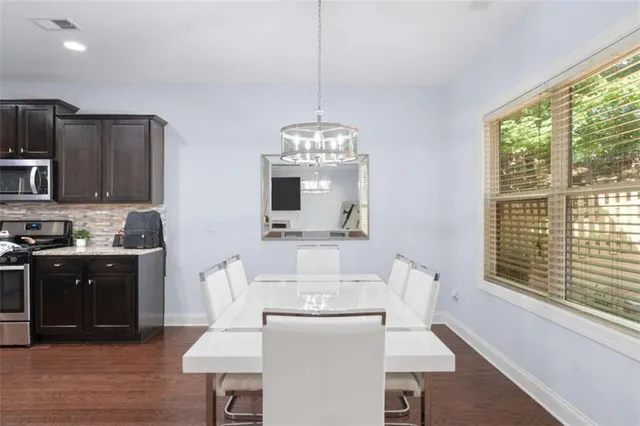 a kitchen with stainless steel appliances granite countertop a stove a sink a microwave a dining table and chairs