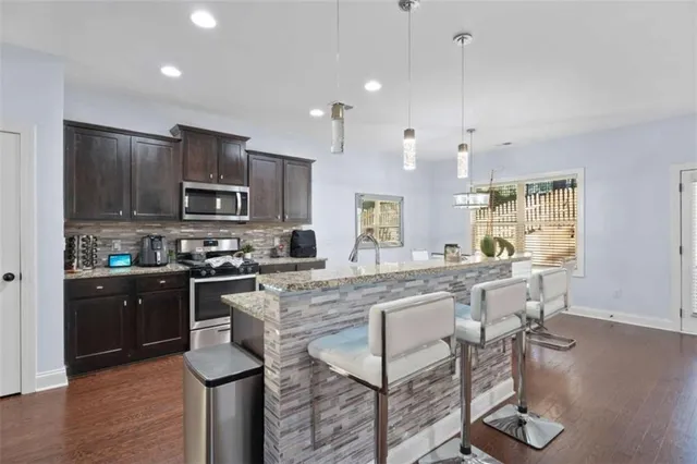 a kitchen with kitchen island granite countertop wooden floors and wooden cabinets