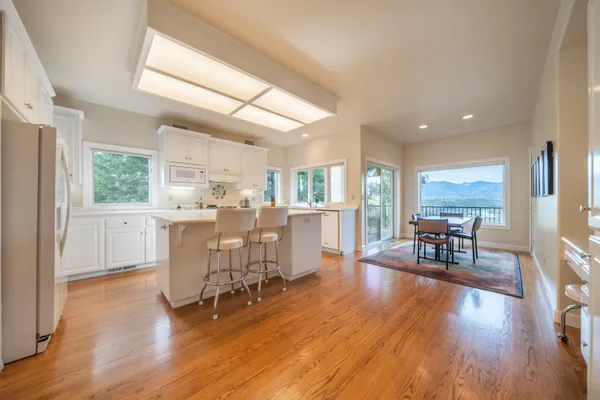 a living room with furniture dining table wooden floor and a large window