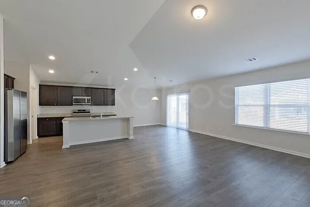a view of kitchen with stainless steel appliances granite countertop a stove top oven a sink and a dishwasher with wooden floor