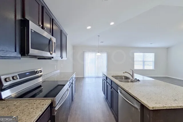 a kitchen with stainless steel appliances granite countertop a stove a sink and a refrigerator